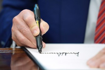 A close-up of Donald Trump's hand as he signs an executive order.